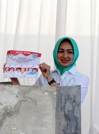Airin menunjukan surat suara sesaat sebelum menyoblos di bilik suara.