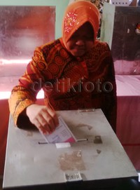 Risma memasukkan surat suara ke kotak suara.