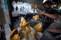 Seorang pekerja tampak sedang melakukan pengecatan produk.