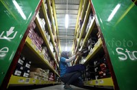 Seorang pekerja merapihkan dagangan.