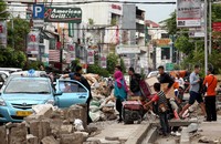 Beberapa pejalan kaki melintas di trotoar yang masih dalam tahap perbaikan.