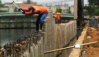 Pekerja menyelesaikan pemasangan turap di Kali Sentiong.