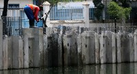 Pekerja menyelesaikan pemasangan turap di salah satu sisi sungai.