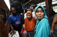 Para penumpang membawa barang bawaan khas mudik seperti tas besar dan kardus.