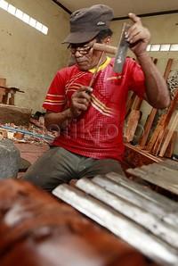 Seorang pekerja sedang melakukan pengerjaan akhir pada salah satu alat musik gamelan.