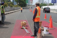 Sejumlah pekerja mengecat jalur  yang akan digunakan sebagai jalur khusus Transjakarta  di Jalan Rasuna Said Kuningan, Jakarta Selatan, Minggu (20/12/2015).