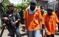Seorang anggota polisi lengkap dengan senjata api laras panjang menjaga para tersangka. Pool/Lamhot Aritonang/detikFoto.     