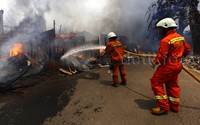 Petugas damkar mencoba memadamkan api yang melanda wilayah Bukit Duri, Manggarai, Jakarta Selatan, Kamis (24/12/2015).
