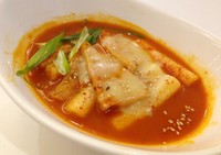 Cheese Tokpokki berisi tteok (rice cake) dan  irisan eomuk (fish cake). Lelehan keju mozzarella menutupi sedikit permukaan kuah merah tokpokki.