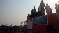 Sejumlah penonton menaiki mobil pemadam kebakaran yang disiapkan di pinggir lintasan balapan.