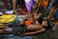 Anak-anak kecil dimintakan berkah oleh orang tua mereka dengan cara diinjak oleh Orang Suci.Ada banyak bocah yang ketakutan sampai menangis, namun ada juga yang tetap tenang dan mengikuti prosesi ritual keagamaan ini sampai selesai (Rupak De Chowdhuri/Reuters)