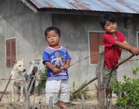 Dua anak kecil berdiri menyaksikan peserta Toba Audax 2016 yang melintas depan rumahnya.