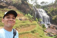 Air terjun mengalir deras dengan persawahan di sekelilingnya Air terjun mengalir deras dengan persawahan di sekelilingnya
