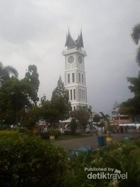 Foto Jam Gadang dari kejauhan di balik pepohonan taman kota Bukit Tinggi. Foto Jam Gadang dari kejauhan di balik pepohonan taman kota Bukit Tinggi.
