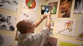 Mantan pelaksana tugas (plt) pemimpin Komisi Pemberantasan Korupsi Mas Achmad Santosa memotret karya seni grafis bertema anti-korupsi yang dipamerkan di TIM. (CNNIndonesia Rights Free/Feri Latief)