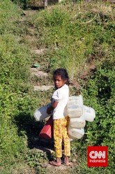 Seorang anak perempuan membawa jeriken ke tempat pengambilan air di pintu masuk desa. Tidak ada air keran untuk mengisi kebutuhan air warga di masing-masing rumah. Setiap desa di Golo Wangkung memiliki tempat pengisian air masing-masing. (CNN Indonesia/ Windratie)