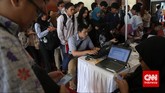 Para pencari kerja antre mengisi formulir lamaran kerja di stan sebuah perusahaan saat pameran bursa kerja di Balai Kartini, Jakarta, Jumat (24/4). (CNN Indonesia/Safir Makki)