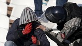 Seorang suporter yang terluka sedang diperiksa polisi. Karena kerusuhan di laga tersebut 35 polisi terluka dan 41 orang suporter ditangkap.