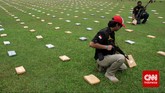 Petugas memeriksa 2,1 ton ganja yang 'dipamerkan' Direktorat Tindak Pidana Narkoba Badan Reserse Kriminal di Lapangan Bhayangkara Mabes Polri, Jakarta, Senin (11/5). Dalam menyita ganja-ganja ini dari jaringan pengedar Aceh, polisi menangkap empat orang di Jakarta Selatan. (CNN Indonesia/Adhi Wicaksono)