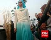 Baju lain yang diperagakan terlihat lebih sederhana. Gaun panjang tersebut berwarna putih dan bergradasi biru muda di bagian bawah. Tumpukan batu swarsovski biru yang senada dengan bagian bawah rok membuat pakaian tersebut terkesan mewah. (CNN Indonesia/Nadi Tirta Pradesha)
