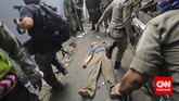 Satpol PP dan Polisi menyelamatkan warga yang terluka saat penggusuran rumah warga di bantaran Kali Ciliwung, Kampung Pulo, Jakarta, Kamis, 20 Agustus 2015. (CNN Indonesia/Adhi Wicaksono)