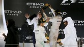 Pebalap Mercedes Lewis Hamilton (kedua dari kiri) dan rekan satu timnya Nico Rosberg merayakan kemenangan sambil mengerjai anggota tim Mercedes lain di podium sirkuit Yas Marina, Abu Dhabi, 29 November 2015. (REUTERS/Hamad I Mohammed)