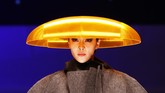 Aksesori kepala berwarna jingga yang menyala-nyala ini menjadi kontras bagi atasan jaket berwarna kelabu dengan detail bertumpuk pada bagian dada. Sekilas material tebalnya mengingatkan pada karpet. (REUTERS/Kim Kyung-Hoon)