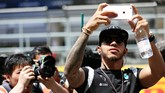 Sementara Lewis Hamilton yang belum juara di lima balapan tetap asik dengan telepon genggam yang tak pernah lepas dari tangannya. Hamilton harus membalap dari posisi paling buncit karena mengalami kerusakan power unite di sesi kualifikasi. (Mark Thompson/Getty Images)