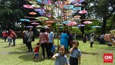 Berbagai instalasi seni payung dibuat meriah dengan warna-warni menarik, sehingga para pengunjung pun tertarik untuk berfoto, seperti dua bocah ini yang merengek minta difoto oleh orang tuanya. (CNN Indonesia/Vega Probo)