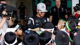 Meskipun kesal karena gagal finis pada seri grand prix di Malaysia pekan lalu, Pebalap Mercedes Lewis Hamilton tetap melemparkan senyum saat menerima permintaan tanda tangan dari bocah-bocah penggemar dirinya di sirkuit Suzuka. (Reuters/Toru Hanai)