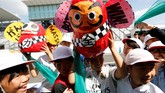 Anak-anak kecil setempat membawa boneka Daruma di pit lane. Boneka Daruma adalah boneka khas Jepang yang dipercaya dapat memberikan keberuntungan yang bagus. (Reuters/Toru Hanai)