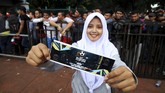 Seorang perempuan yang rela mengantri dengan bahagia menunjukkan tiket leg pertama semifinal Piala AFF yang berhasil ia beli. (ANTARA FOTO/Rivan Awal Lingga)