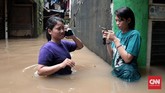 Warga di Jalan Bina Warga kawasan Rawajati, Jakarta Selatan, yang terkena banjir hingga satu meter lebih sejak Selasa (21/2) pagi, tampak berkomunikasi dengan telepon selulernya. Mereka banyak yang memberi kabar kepada sanak saudaranya mengenai musibah banjir yang dialaminya. (CNN Indonesia/Andry Novelino)