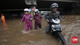 Tak sedikit pengendara sepeda motor yang nekat menembus banjir yang tidak dapat dilalui kendaraan roda dua di bawah ruas Jalan Tol Bintara, Bekasi, Selasa (21/2). Tingginya genangan yang mencapai selutut orang dewasa membuat mesin-mesin sepeda motor mati akibat busi basah. (CNN Indonesia/Safir Makki)