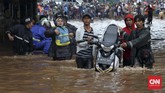 Arus lalu lintas terputus akibat banjir di bawah ruas Jalan Tol Bintara, Bekasi, Selasa (21/2). Warga membantu pengendara sepeda motor dengan menggunakan gerobak untuk bisa menembus banjir yang tak dapat dilalui kendaraan di bawah ruas tol tersebut. (CNN Indonesia/Safir Makki)