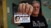Mereka mencari namun tidak dapat dengan leluasa menunjukkan kebanggaan mereka terhadap the Beatles. Seperti seorang pria yang mengoleksi kartu mengemudi John Lennon ini. (AFP PHOTO / YAMIL LAGE)