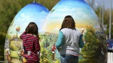 Dua anak perempuan memandang hiasan telur paskah setinggi dua meter di Koprivnica, Kroasia pada 9 April 2017. (REUTERS/Antonio Bronic)