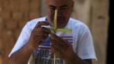 Di El Salvador, seorang pria membuat hiasan salib dari batang pohon palem menjelang prosesi Los Cristos, bagian dari perayaan Pekan Suci di negaranya, 13 April 2017. (REUTERS/Jose Cabezas).