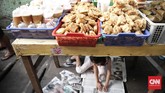 Seorang anak membaca koran sambil menemani orang tuanya menjajakan makanan khas buka puasa di pasar takjil Kebon Kacang. (CNN Indonesia/ Hesti Rika)