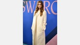 Tampil beda dan berseberangan dengan saudarinya, Gigi Hadid mengenakan gaun krem dan coat rancangan The Row. Ia hanya memberi sedikit aksesori di leher. (Dimitrios Kambouris/Getty Images/AFP)