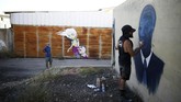 Zero Cents punya ekspresi yang berbeda-beda. Ia merupakan seniman keturunan Amerika dan Israel. Selain menggambar sepasang bocah lelaki dan perempuan, ia juga melukis sesosok berbusana rapi seperti setelan politisi. (REUTERS/Amir Cohen)