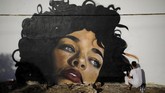 Seniman Amerika yang mengklaim diri bernama Drew misalnya, menggambar wajah perempuan dengan rambut ikal dan tubuh seperti tertanam di tanah. (REUTERS/Amir Cohen)