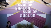 Seniman Hawaii lainnya, Noelle Enright membuat dinding lebih berwarna dengan tulisan salam khas Yahudi: Shalom, shalom, shalom, shalom, shalom. (REUTERS/Amir Cohen)