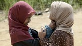 Mereka juga mendapat bantuan pakaian sehingga tak lagi harus mengenakan cawat seadanya. Tampak dua gadis Orang Rimba tengah mengenakan jilbab dan bersiap-siap untuk belajar mengaji. (AFP PHOTO / GOH CHAI HIN)