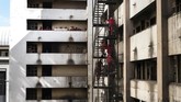 Ratusan pekerja berpakaian khas merah-merah itu menertibkan apartemen tua yang sudah ternoda asap kompor dan dihiasi jendela pecah. (AFP photo/Marco Longari)