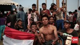 Warga membagi hasil hadiah dengan tim pemanjat pinang saat mengikuti lomba panjat pinang kolosal di Pantai Carnaval Ancol. (CNN Indonesia/Andry Novelino)