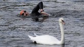 Perenang melewati seekor angsa di Klub Renang Serpentine di London, Inggris, 6 Agustus 2017. (REUTERS/Peter Nicholls)
