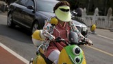 Seorang wanita menggunakan pelindung muka dan kacamata hitam untuk melindungi diri dari matahari, sembari menggendarai skuter di Beijing, China, 14 Agustus 2017. (REUTERS/Thomas Peter)