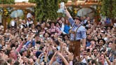 Seorang pengunjung memperoleh respons meriah setelah meminum segelas penuh bir dalam perayaan Oktoberfest. (AFP PHOTO/Christof STACHE)
