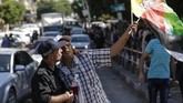 Seorang polisi berpose untuk wefie dengan seorang pria yang mmengibarkan bendera Palestina saat orang-orang berkumpul di Kota Gaza untuk merayakan rekonsiliasi Hamas dan Fatah. (AFP PHOTO / MAHMUD HAMS).